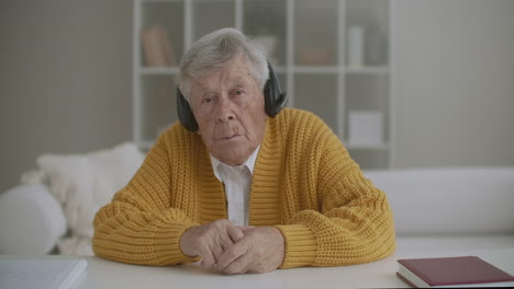 My-grandmother-80-years-old-I'm-looking-at-the-camera-listening-while-sitting-in-headphones.-Remote-communication.-Remote-call-via-video-link.-High-quality-4k-footage